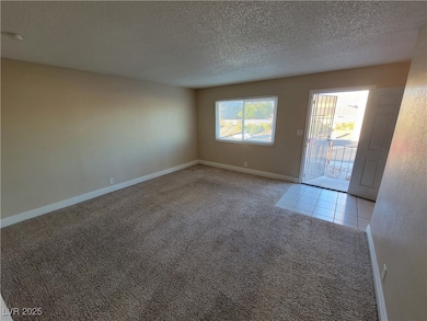 Unfurnished living room featuring carpet flooring and a textured ceiling