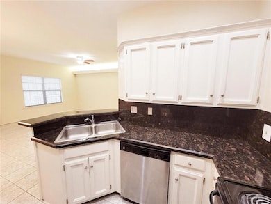 Kitchen with stainless steel dishwasher, a sink, a peninsula, black electric range oven, and light tile patterned floors