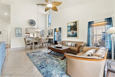 Living room with light tile patterned flooring, arched walkways, ceiling fan, a towering ceiling, and a chandelier