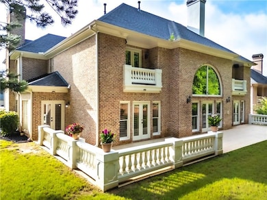 Back of house with french doors, a chimney, brick siding, and a lawn