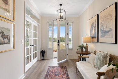 Entrance foyer featuring a chandelier, french doors, healthy amount of natural light, wood finished floors, and ornamental molding