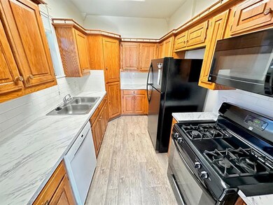 Kitchen with black appliances, light wood finishe