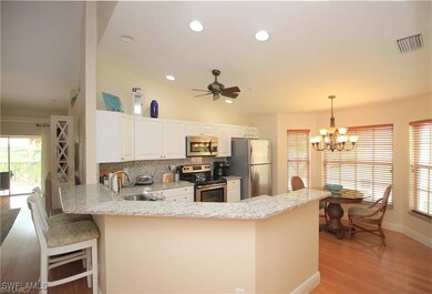 Kitchen featuring ceiling fan with notable chandelier, decorative light fixtures, stainless steel appliances, kitchen peninsula, and light wood-type flooring