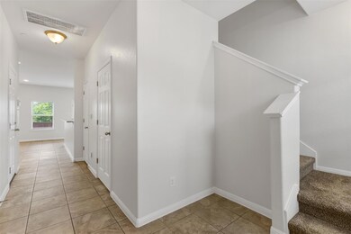 Hallway with light tile patterned floors and stai