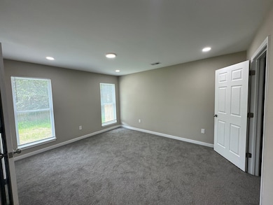 Unfurnished room featuring dark carpet, healthy amount of natural light, and recessed lighting