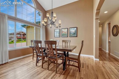 Dining room with wood finished floors, a chandelier, baseboards, lofted ceiling, and recessed lighting