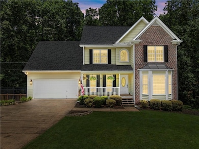 Traditional home with covered porch, a garage, driveway, a front yard, and a shingled roof