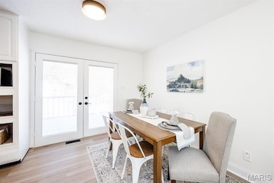Dining room with light wood-style floors and french doors