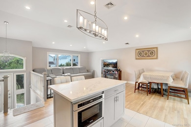 Kitchen with a chandelier, open floor plan, light stone counters, recessed lighting, and a kitchen island