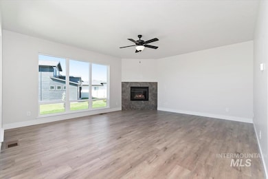 Unfurnished living room with a premium fireplace, light wood finished floors, and a ceiling fan