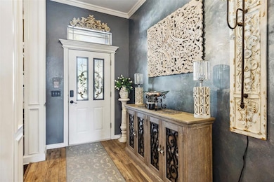 Entrance foyer with wood finished floors, ornamental molding, and baseboards