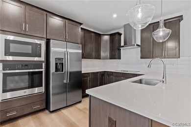 Kitchen with wall chimney range hood, light hardwo