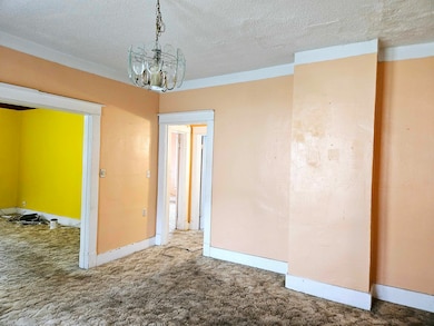 Carpeted empty room featuring a notable chandelier
