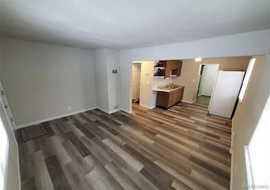 Unfurnished living room featuring dark wood finished floors and baseboards