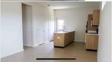 Kitchen featuring a peninsula, a sink, light countertops, light wood-type flooring, and baseboards