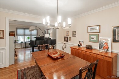 Dining area with crown molding, an inviting chandelier, and light wood-type flooring