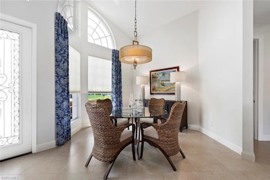 Dining room featuring healthy amount of natural light, light tile patterned floors, high vaulted ceiling, and baseboards