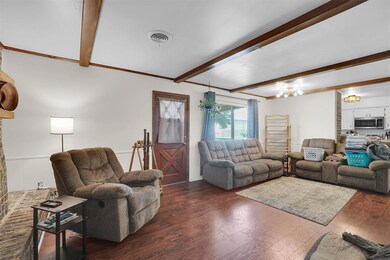 Living room featuring beam ceiling, dark wood-type flooring, and crown molding