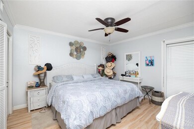 Bedroom with ceiling fan, light wood-type flooring, crown molding, and a closet