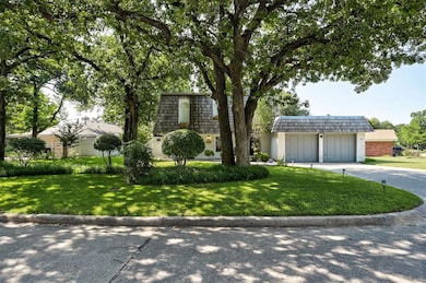 View of property featuring mansard roof, driveway, a front yard, and brick siding