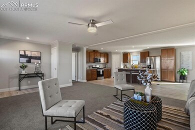 Carpeted living room with ceiling fan and crown mo