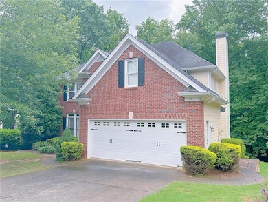 View of home's exterior featuring a chimney, driveway, an attached garage, and brick siding
