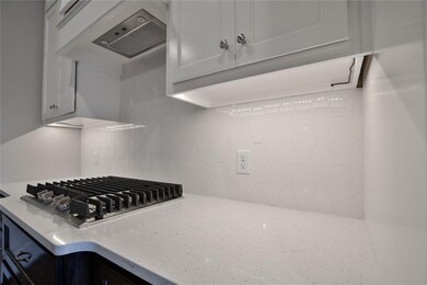 Kitchen with stainless steel gas cooktop, light st