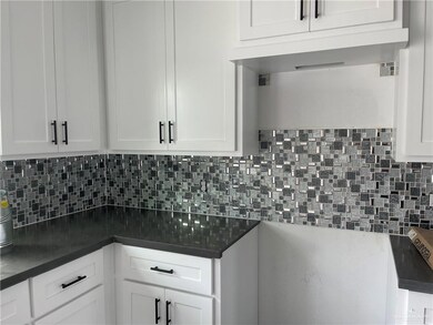 Kitchen featuring decorative backsplash, white cabinetry, and sink