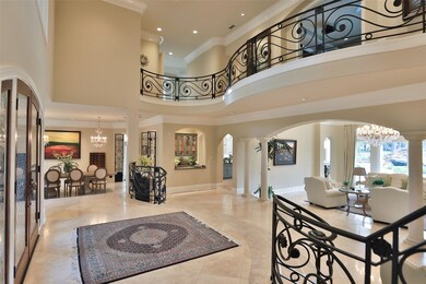 The richly detailed two story foyer features a raised entry with glowing Travertine floors extending three steps to the formal living room and dining room. The wrought iron railing frames the second floor curved balcony beautifully. 
