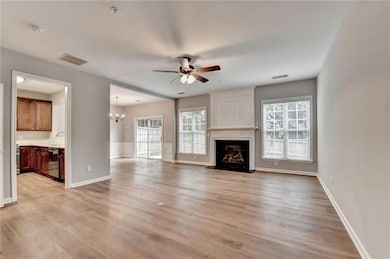 Unfurnished living room with a ceiling fan, a fireplace, a chandelier, and light wood-style floors