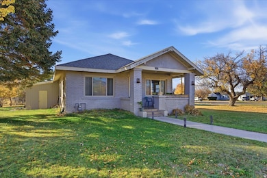View of front of property featuring brick siding, a front yard, a porch, and a shingled roof