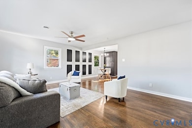 Living room with healthy amount of natural light, wood finished floors, ceiling fan, and a chandelier