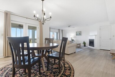 Dining area featuring ceiling fan, light wood-style floors, a fireplace, and a chandelier