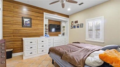 Bedroom featuring light tile patterned floors, wood walls, and ceiling fan