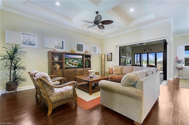 Living room featuring crown molding, coffered ceiling, ceiling fan, beamed ceiling, and dark wood-type flooring