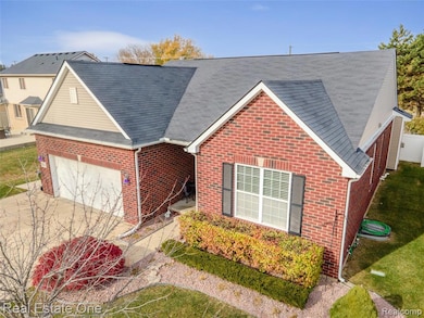 View of front of property with a shingled roof, concrete driveway, brick siding, and a garage