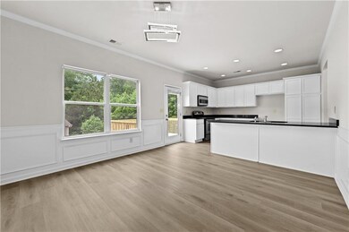 Kitchen featuring appliances with stainless steel finishes, dark countertops, ornamental molding, a sink, and a wainscoted wall