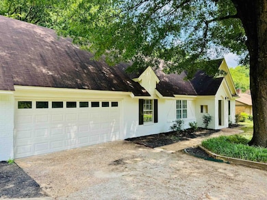View of front of property with brick siding, an attached garage, and driveway