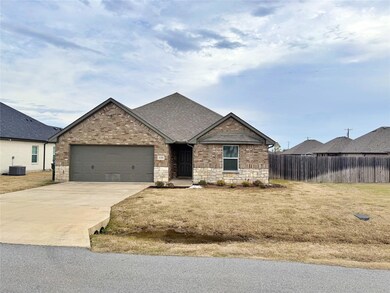 View of front of home with a garage, a front yard, and central air condition unit