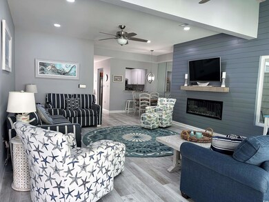 Living room with a ceiling fan, wood finished floors, recessed lighting, and a large fireplace