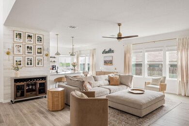 Living room with ceiling fan, visible vents, and 