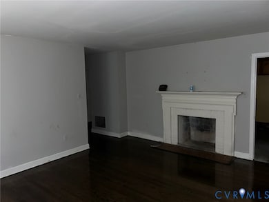 Unfurnished living room featuring dark wood finished floors and a brick fireplace