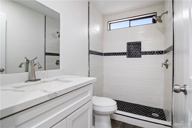 Bathroom featuring vanity, toilet, and tiled shower