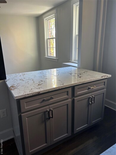 Kitchen featuring gray cabinetry, light stone countertops, and dark wood-style flooring