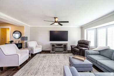 Living area featuring a textured ceiling, wood finished floors, ceiling fan, and ornamental molding