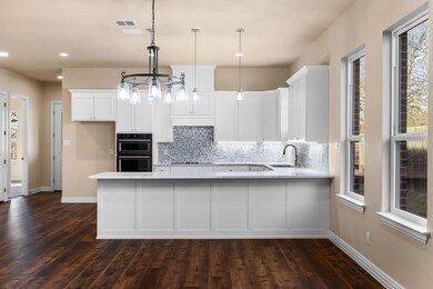 Kitchen with sink, white cabinetry, hanging light 