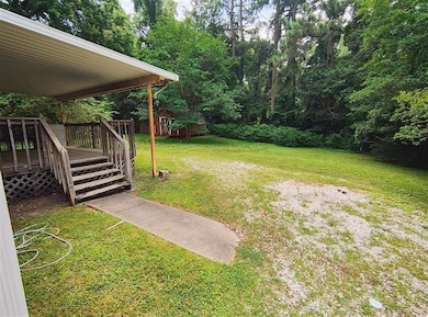 View of green lawn with a deck and a storage unit