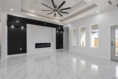 Unfurnished living room featuring a raised ceiling and ceiling fan