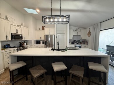 Kitchen with backsplash, a skylight, dark wood-style flooring, lofted ceiling, and appliances with stainless steel finishes