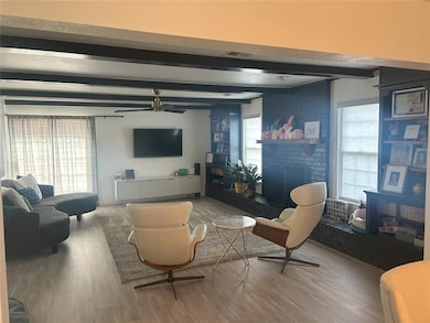 Living room featuring beamed ceiling, a brick fire